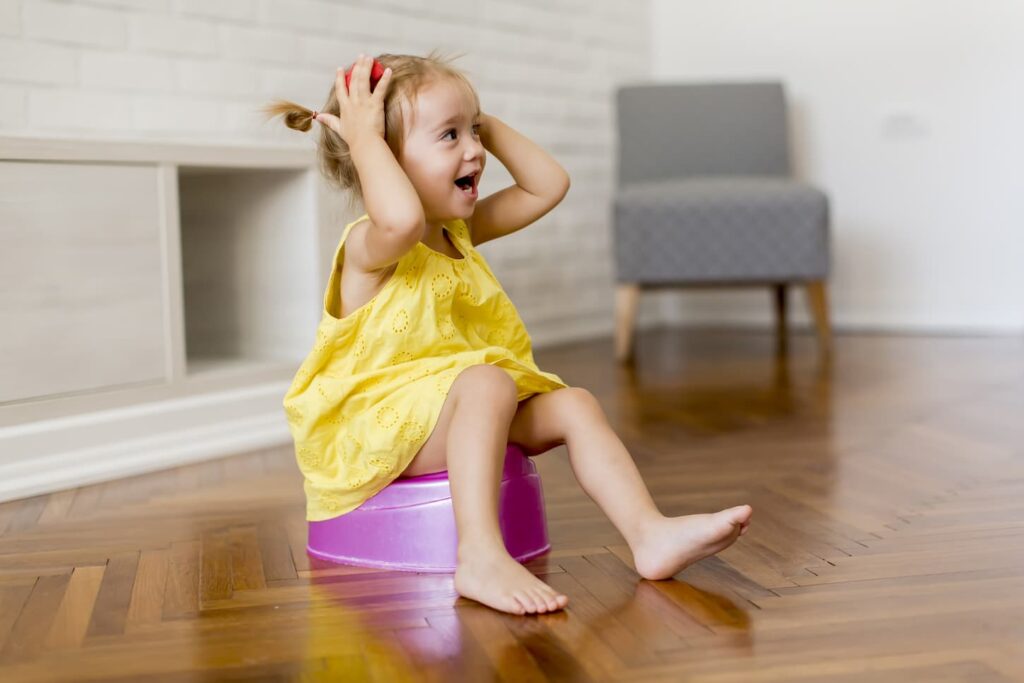 An image of a happy Little girl on the potty in the room.