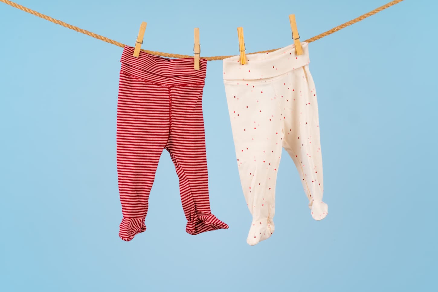 An image of Baby girl clothes pinned on a clothesline against blue background.