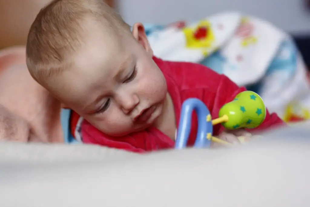 An image of an adorable baby playing and biting her rattle toy.