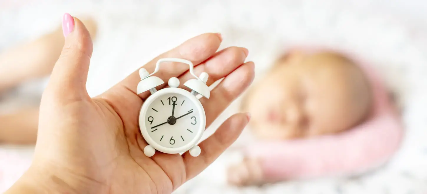 An image of a baby sleeping and a mini-alarm clock.