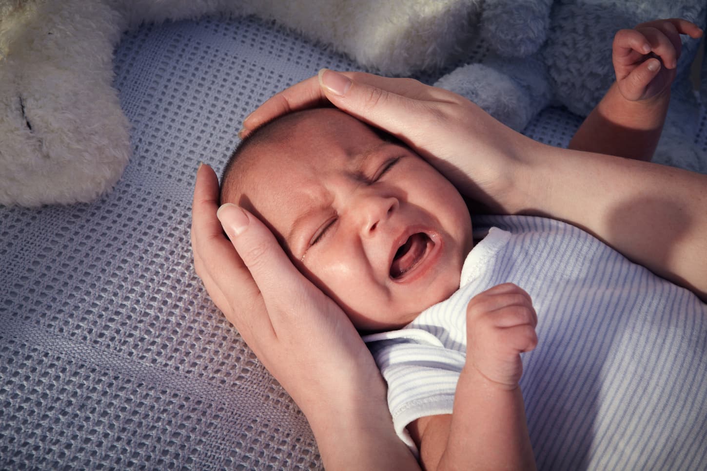 An image of a baby boy crying in his crib before going to bed.