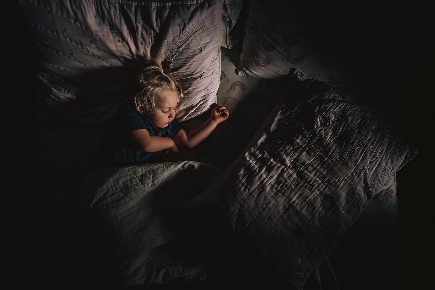 An image of a child sleeping in a dark room.