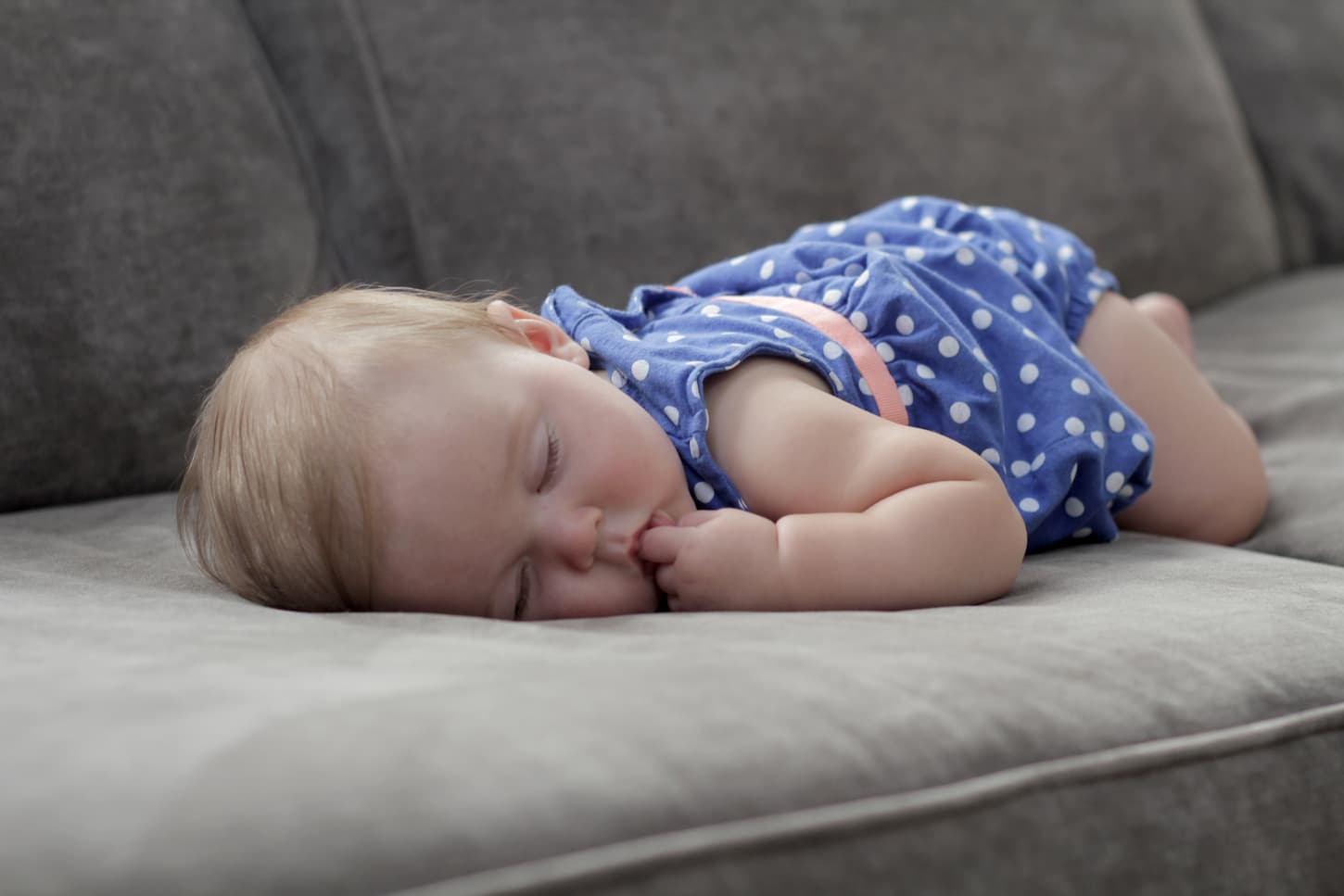 An image of a baby girl sleeping on the couch.