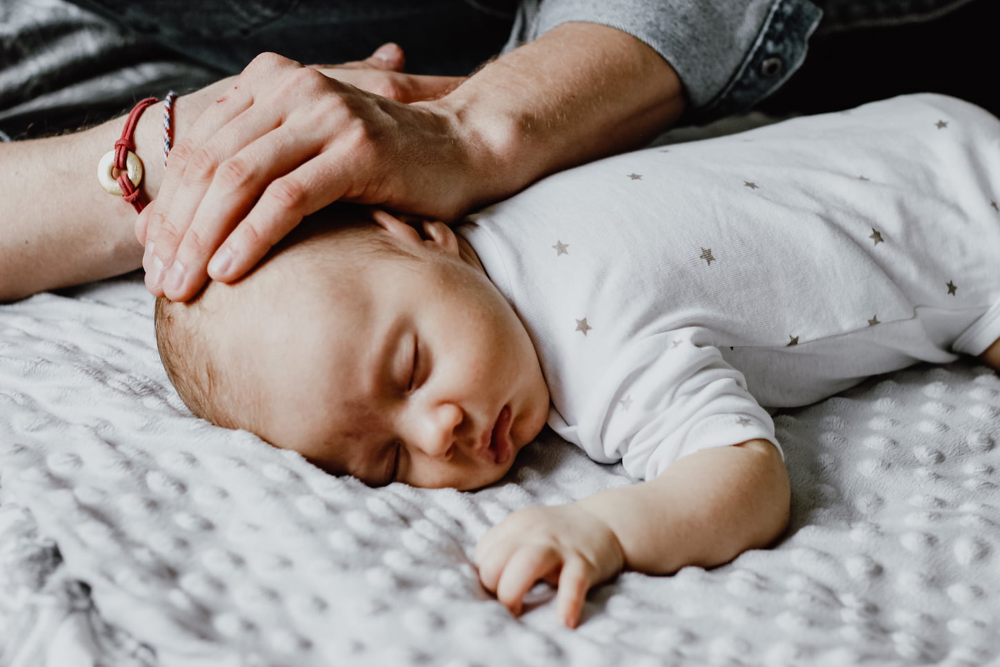 An image of a sleeping baby under the care of his father.