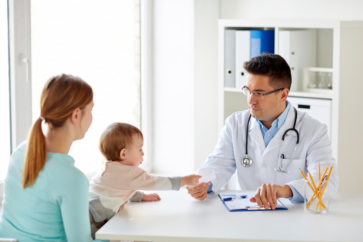 An image of a woman with her baby and a pediatrician at the clinic.
