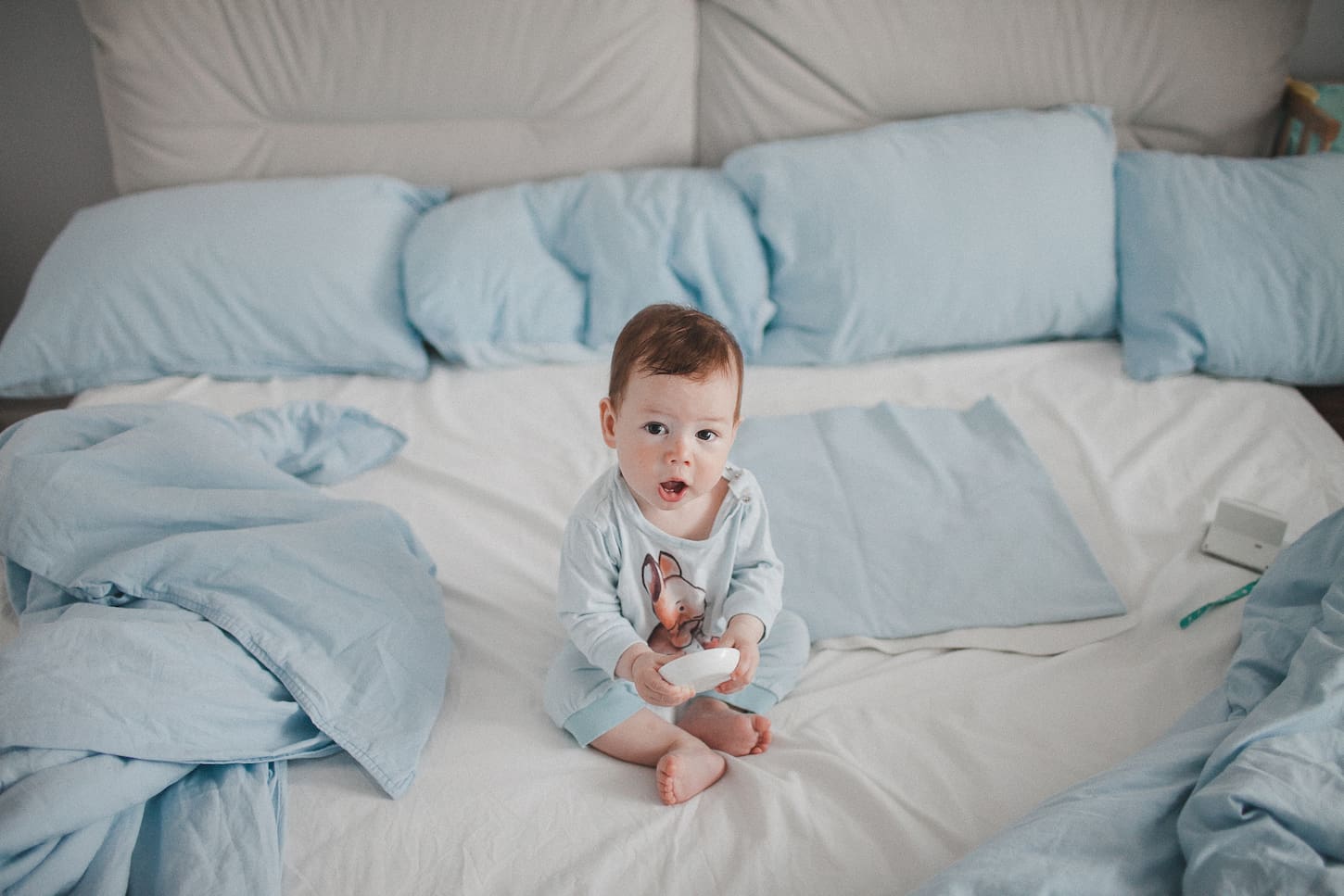 An image of a baby boy sitting in a spacious bed.