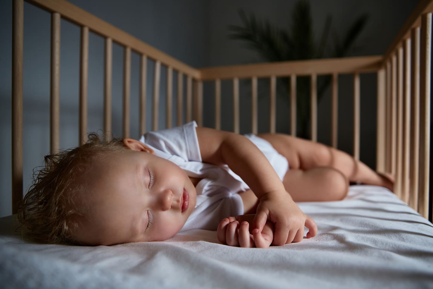 An image of a cute baby sleeping at night in a cradle.