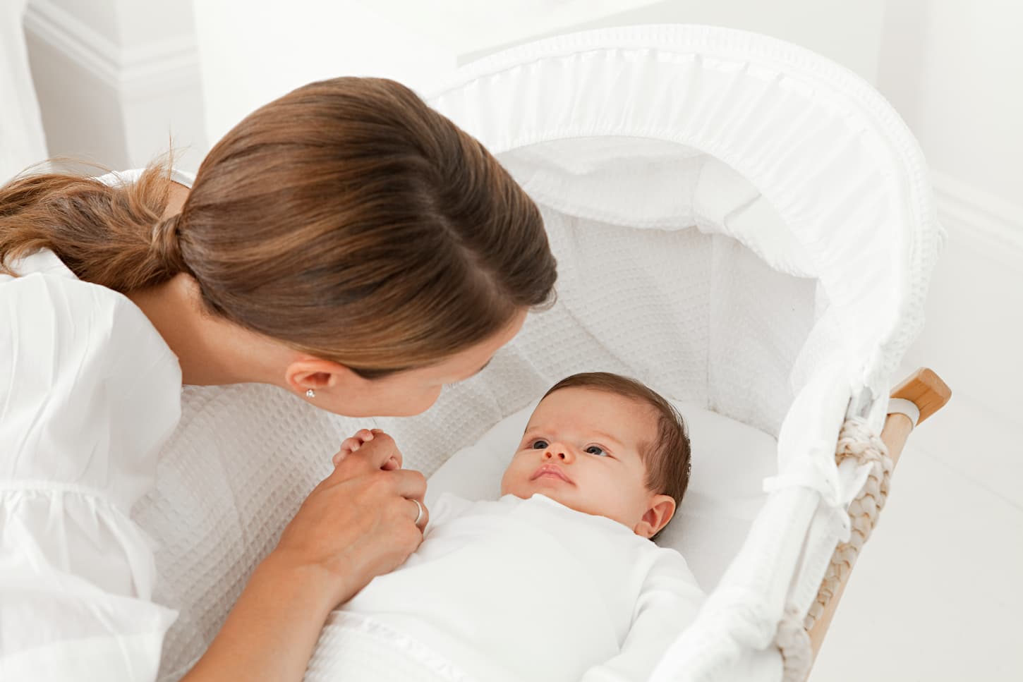 An image of a Mother with her baby in a bassinet.