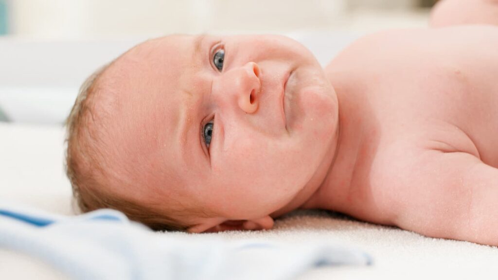 An image of an unhappy crying newborn baby lying on changing table.