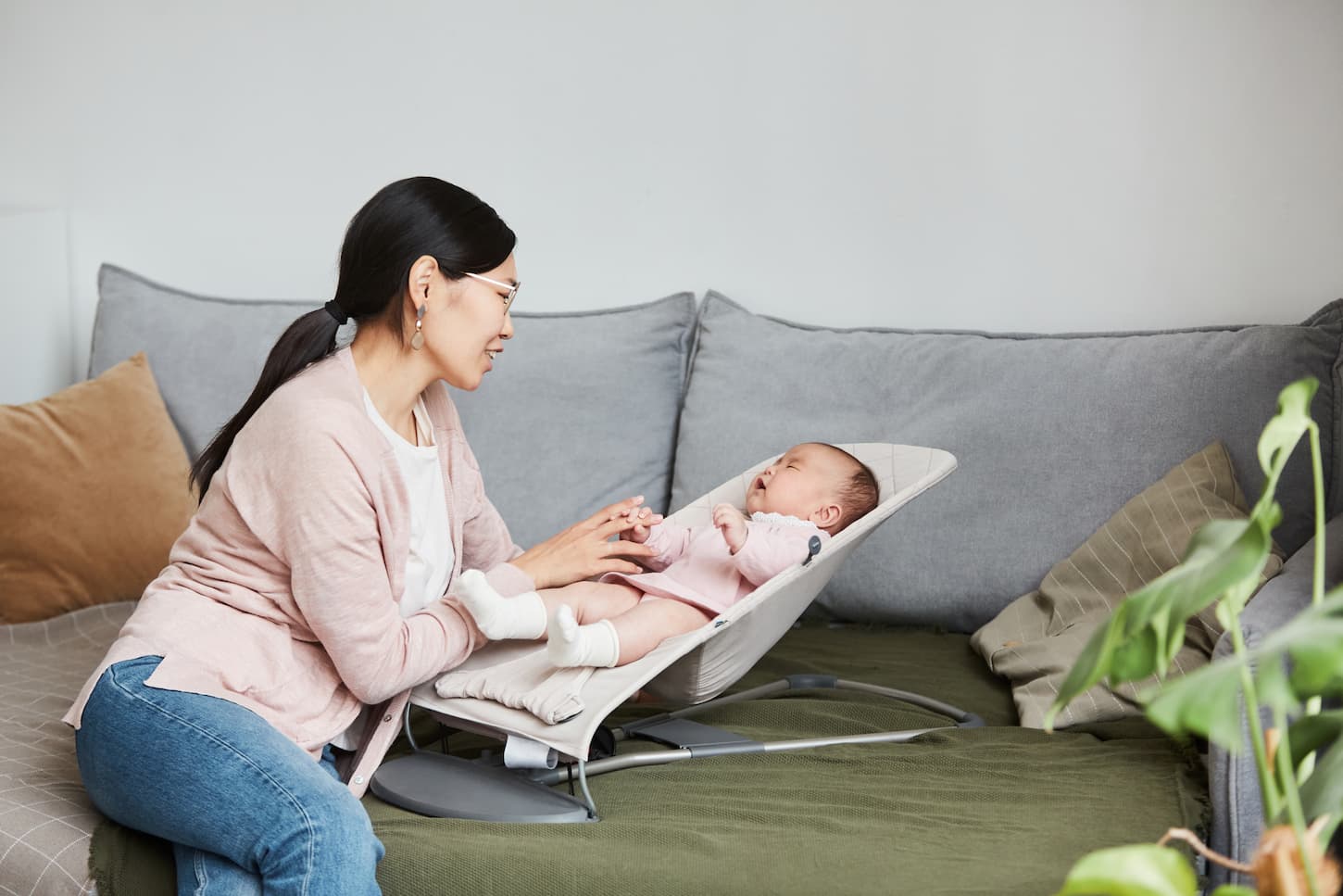 An image of a young mother talking to her baby while she crying in the lounge chair in the living room.