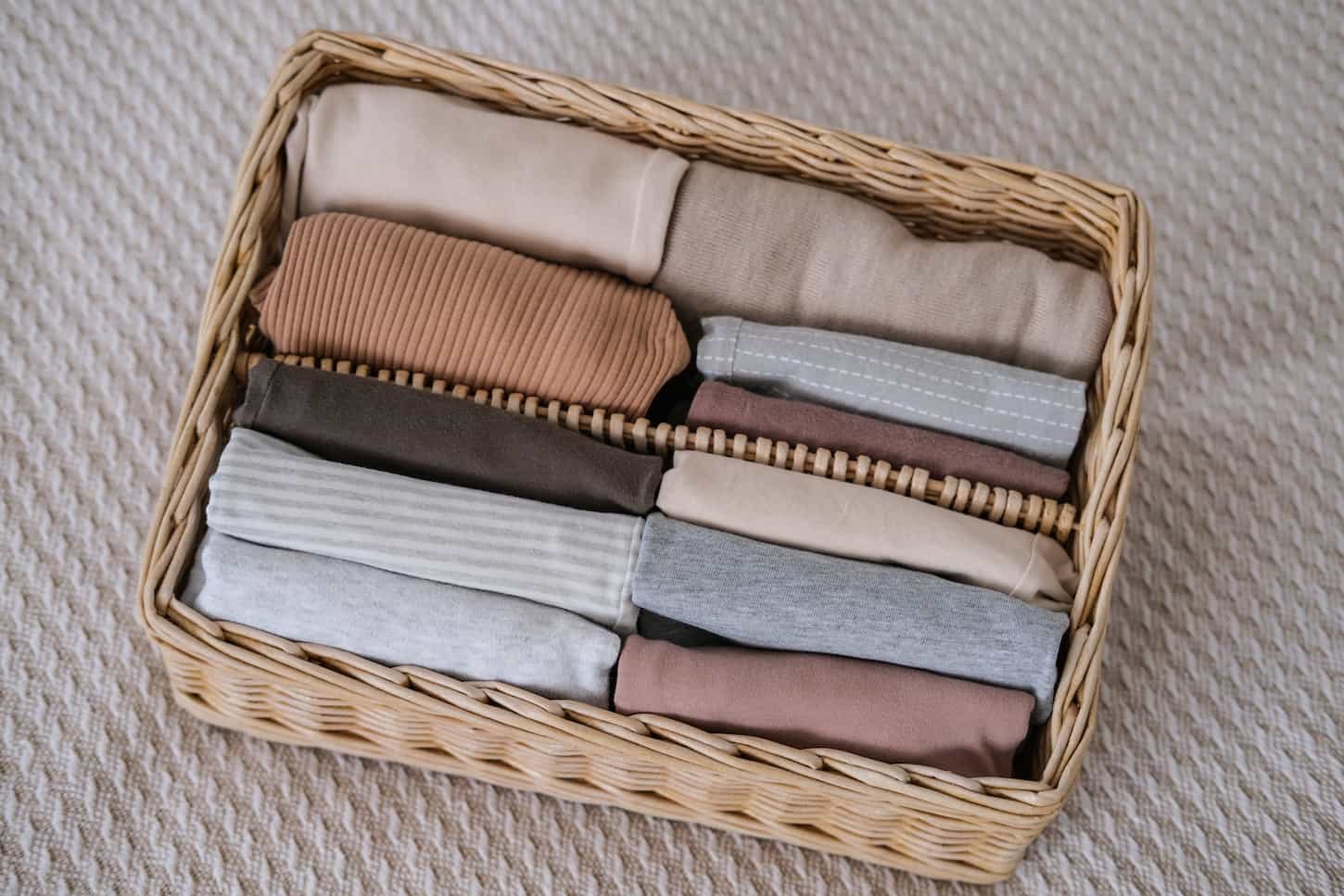 An image of Baby clothes in a wicker container.
