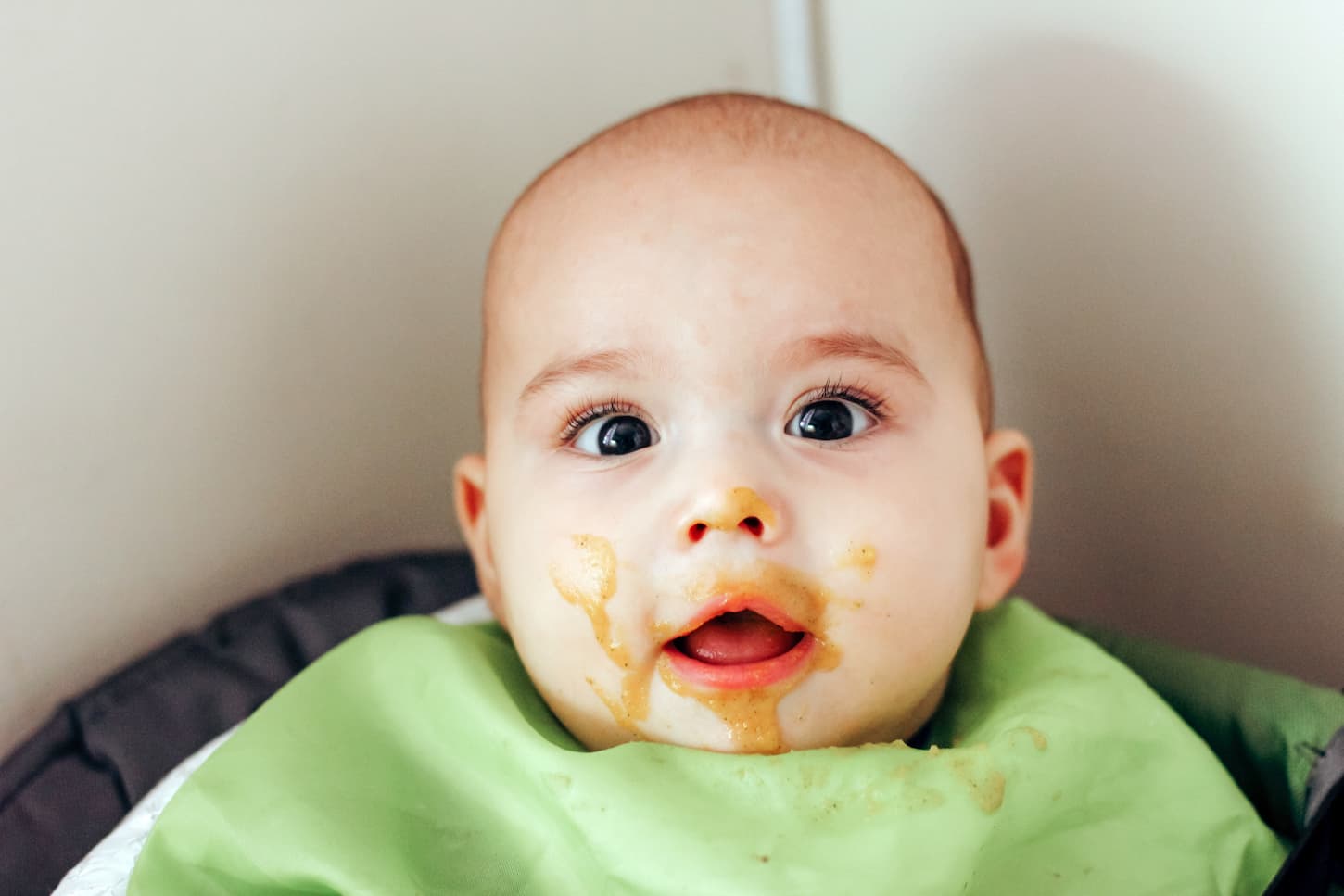 An image of a Happy smiling baby with a dirty face during feeding time.