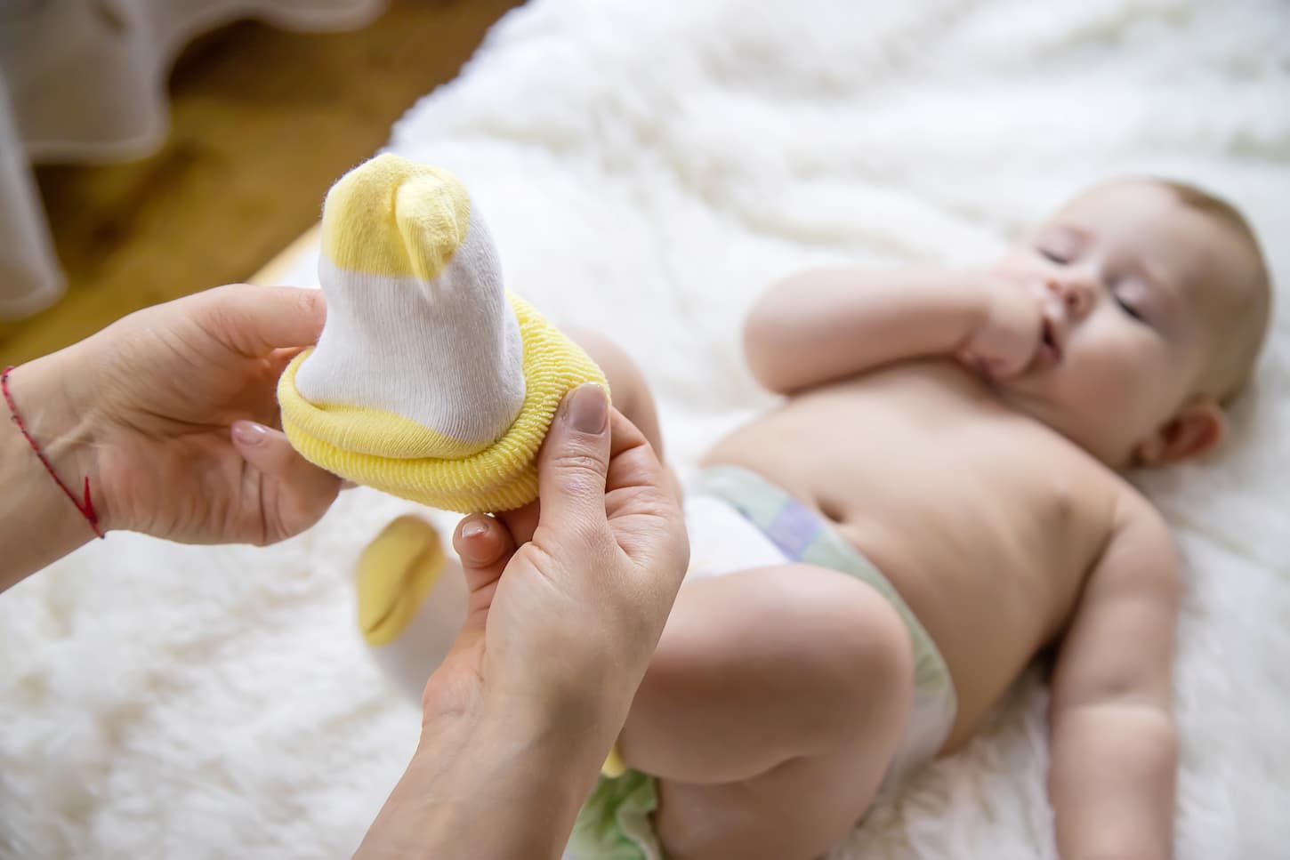 An image of a Mother putting socks on the little baby.